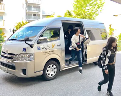 垂水駅付近で送迎シャトルバスに乗るスタッフの写真
